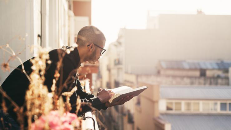 Guy Reading a Book on Balcony