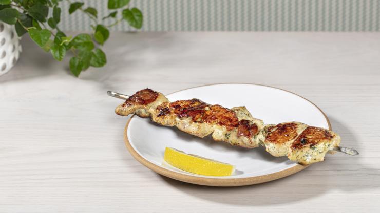 Chicken kebab with summer savory marinade on a plate with a lemon wedge