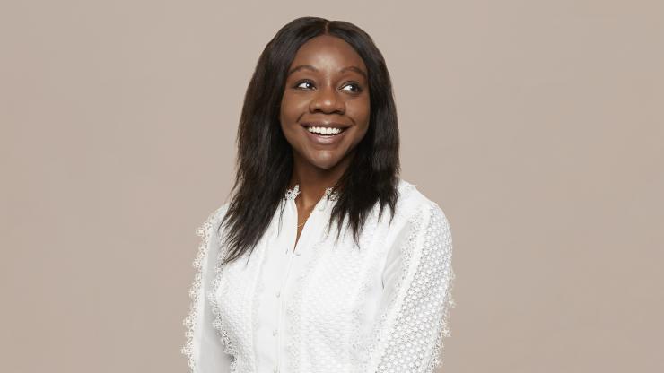 Chika Okoli stands smiling and looking off happily