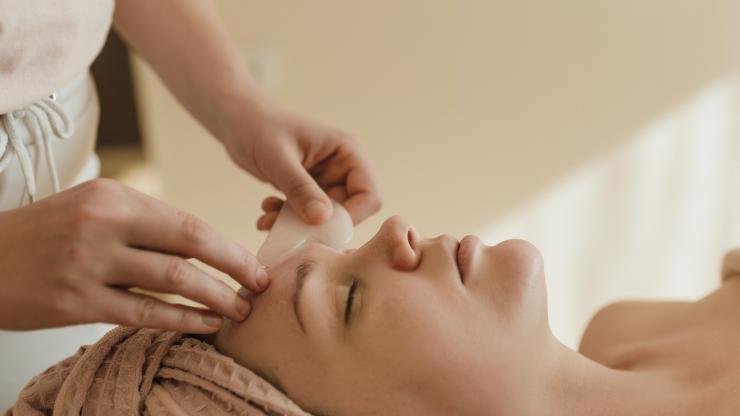Woman lying on massage table getting a facial gua sha treatment
