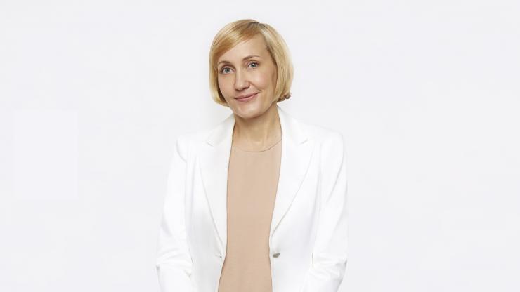 Jessica Sowards, dressed in a white blazer and peach blouse, smiles at the camera.