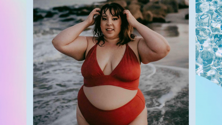Alicia McCarvell poses in a bathing suit on the beach, smiling at the camera.