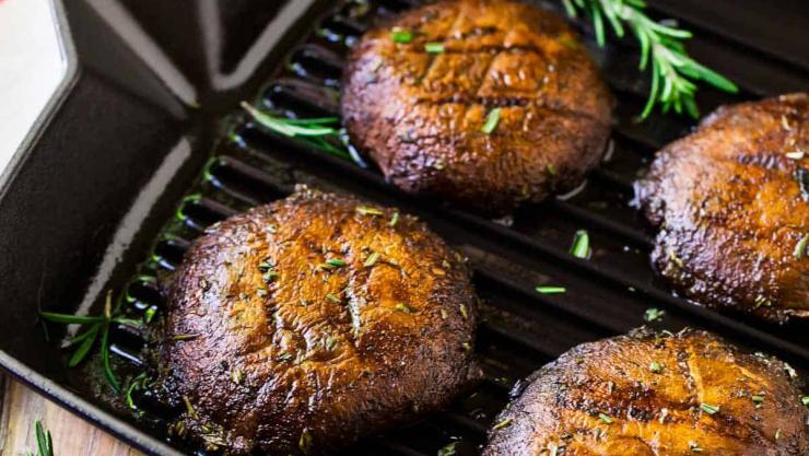 Grilled portabello mushrooms on a griddle pan with rosemary.