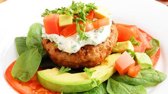 Turkey burger with avocado, tomatoes and basil.