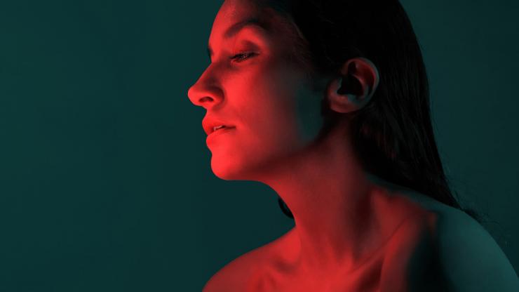 A woman's face glows in a red light.