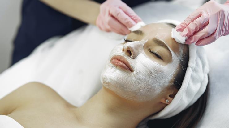 Close up of a woman getting a facial treatment as esthetician applies products to her skin.